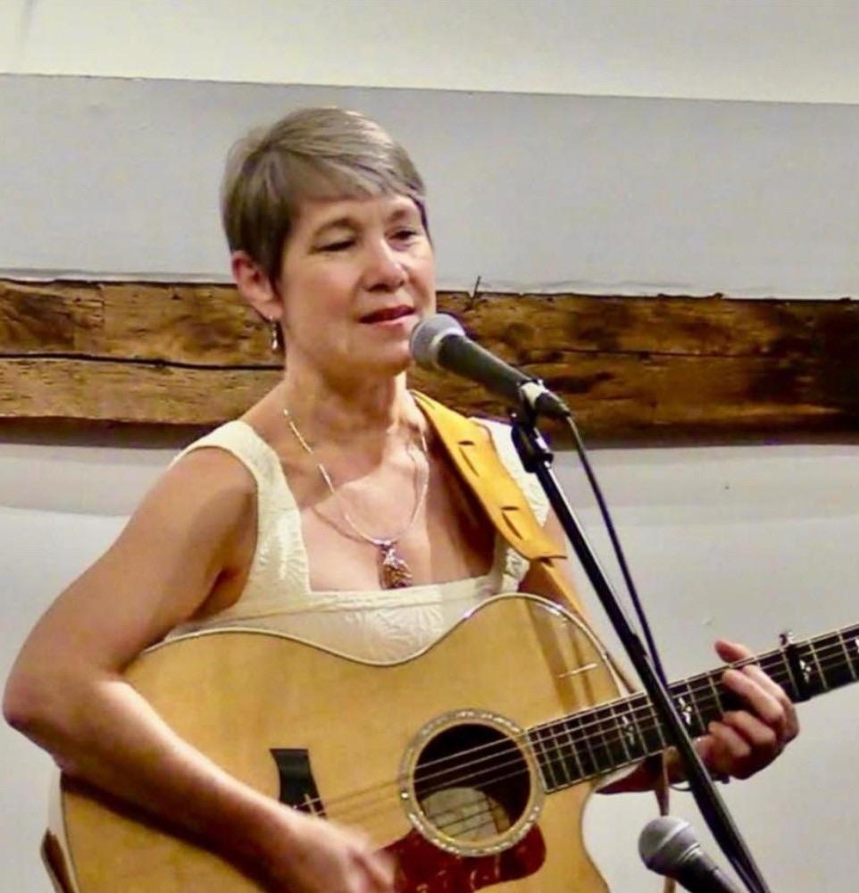 Christine Cote’ Baillargeon singing with an acoustic guitar